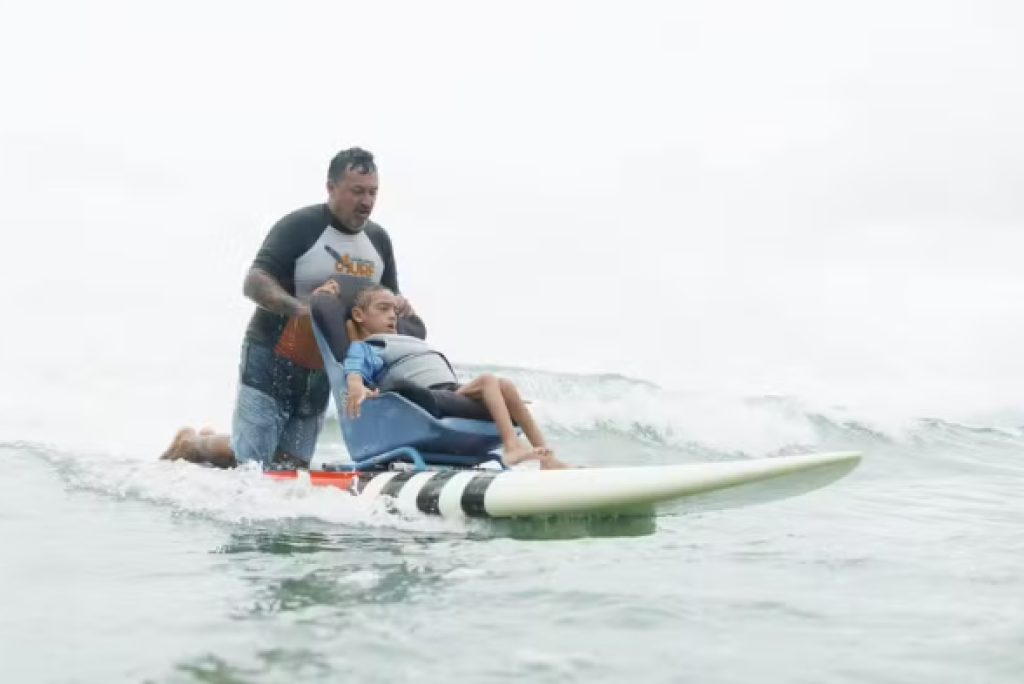 Pais criam prancha de surfe adaptada para filho com paralisia se aventurar no mar em Ubatuba