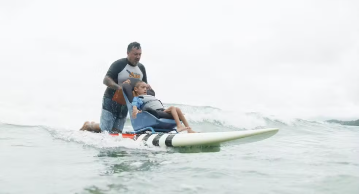 Pais criam prancha de surfe adaptada para filho com paralisia se aventurar no mar em Ubatuba